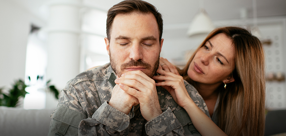 Military man is comforted by his wife.