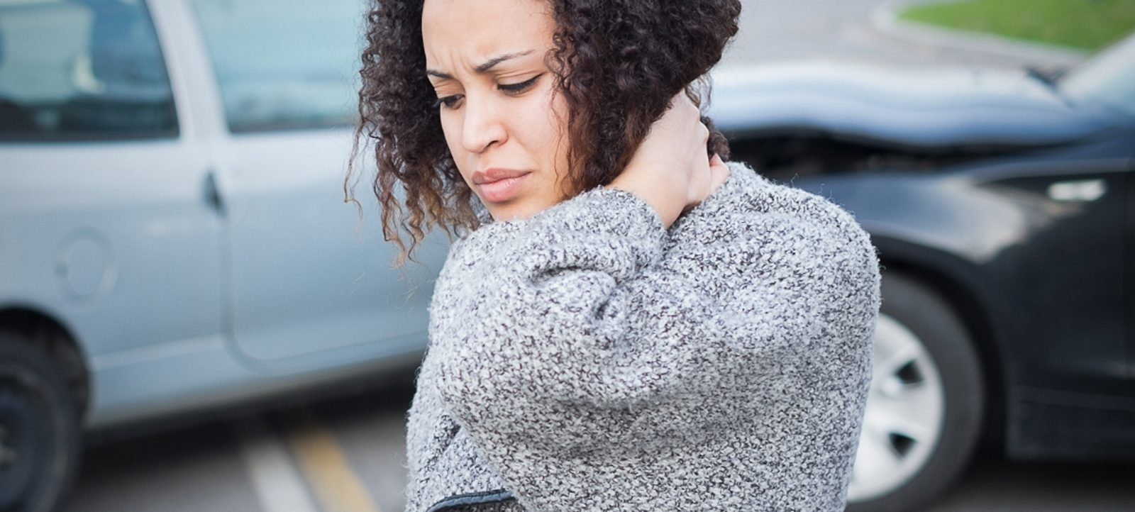 Woman holds her neck in pain after a whiplash auto accident.